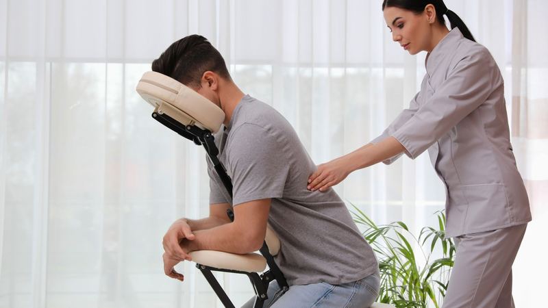 Chair massage therapist helping a seated client in Las Vegas